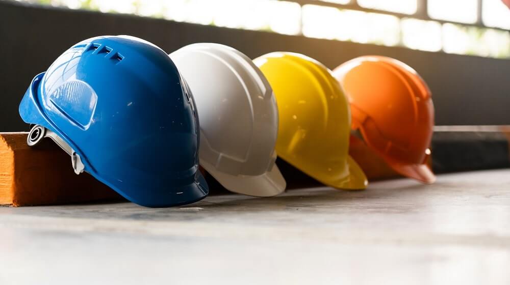 Capacetes de obra nas cores azul, branco, amarelo e laranja