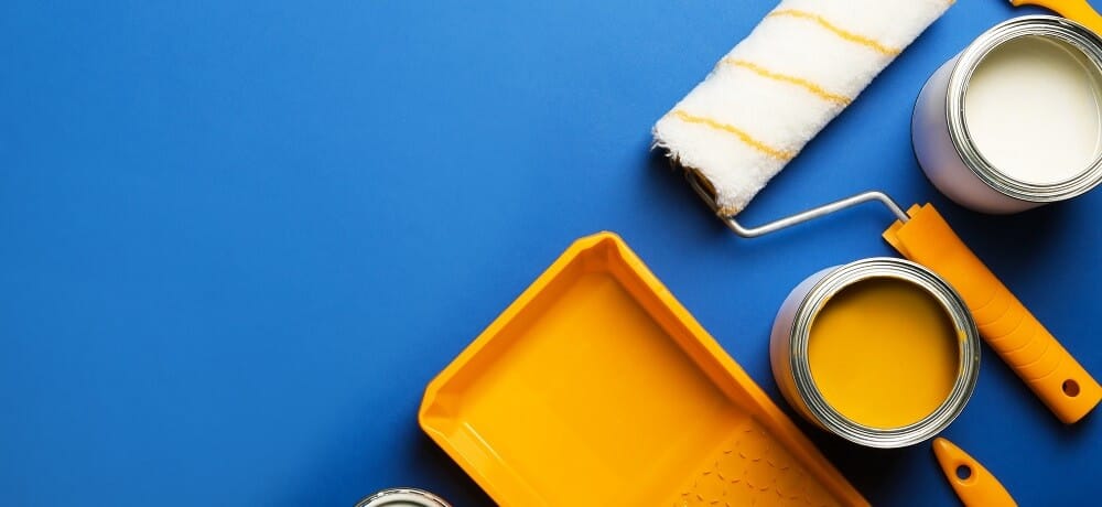 Materiais de pintura, incluindo pincéis e latas, em um fundo azul.